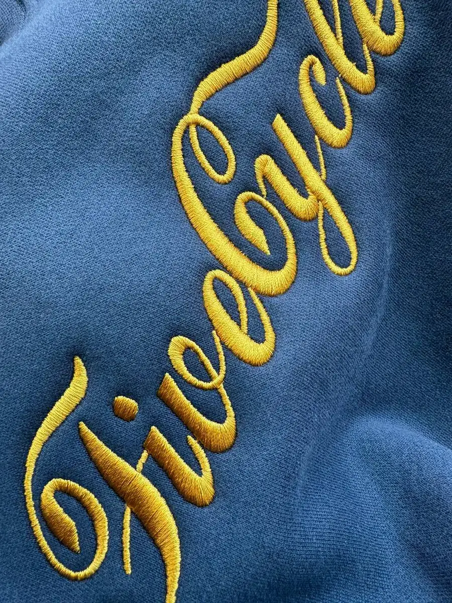 Gold script embroidery across the chest of a navy sweatshirt