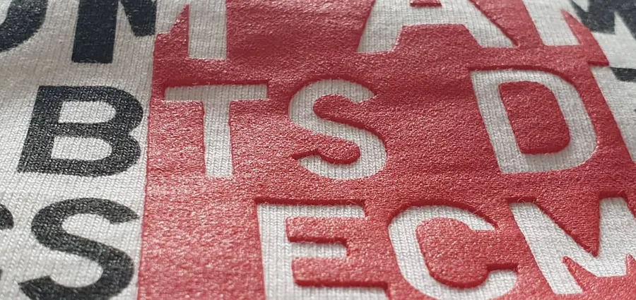 Red puff print lettering on a white tee, close up